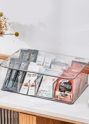 Clear organizer with coffee packets on a table with a vase and cup in the background